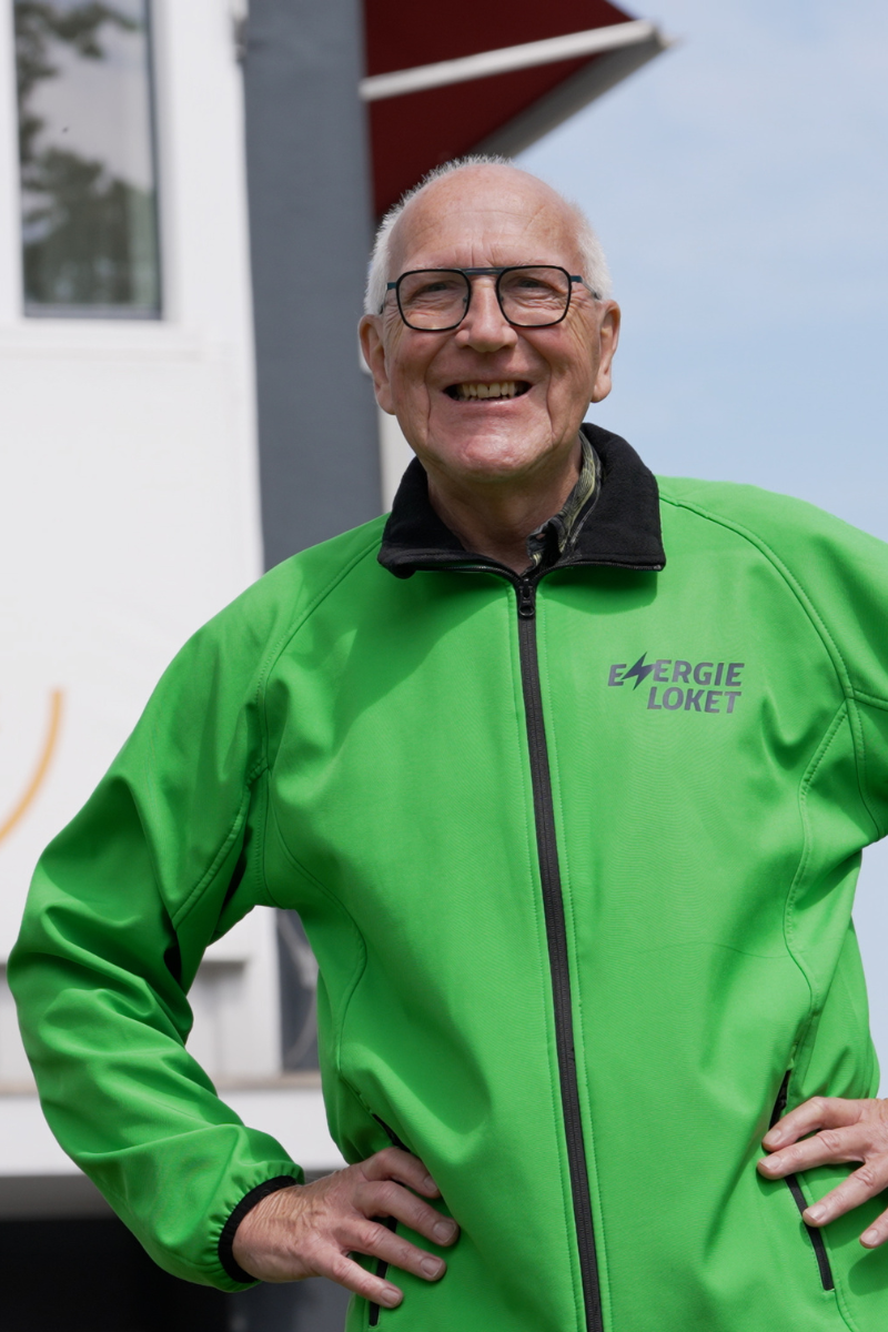 Energiecoach in groene jas met logo helpt bewoners met advies over woningverduurzaming en energiebesparing.